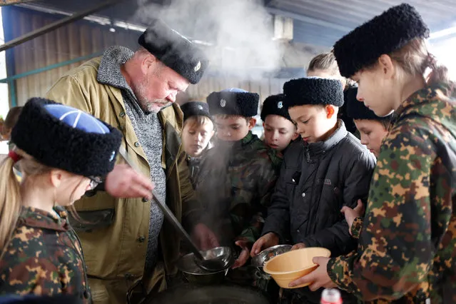 Children get their meals during military training undergone by students of the General Yermolov Cadet School and members of a Cossack community at a boot camp of the Russkiye Vityazi (Russian Knights) military patriotic club in the village of Sengileyevskoye in Stavropol region, Russia, November 1, 2016. (Photo by Eduard Korniyenko/Reuters)