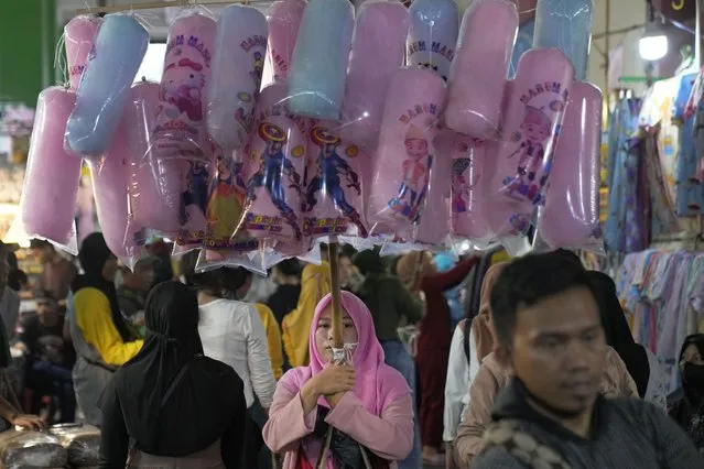 A woman sells cotton candy at Tanah Abang market in Jakarta, Indonesia, Friday, April 14, 2023. Indonesians flock markets and shopping malls in the capital as they shop for food and new clothing in preparation for Eid al-Fitr holiday next week that marks the end of the holiest month in Islamic calendar. (Photo by Dita Alangkara/AP Photo)