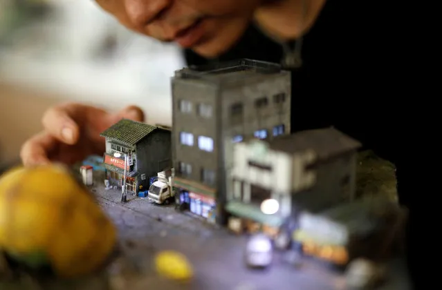 Taiwanese artist Hank Cheng poses with his miniature model of street scenes in New Taipei City, Taiwan on June 17, 2018. (Photo by Tyrone Siu/Reuters)