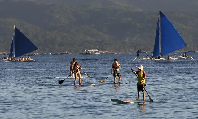 Tourists learn to paddle in the sea by the country's most famous beach resort island of Boracay, in central Aklan province, Philippines, Tuesday, April 24, 2018. Thousands of workers will be affected when the island closes after Philippine President Rodrigo Duterte ordered its closure on April 26 for up to six months after saying the waters off its famed white-sand beaches had become a “cesspool” due to overcrowding and development. (Photo by Aaron Favila/AP Photo)