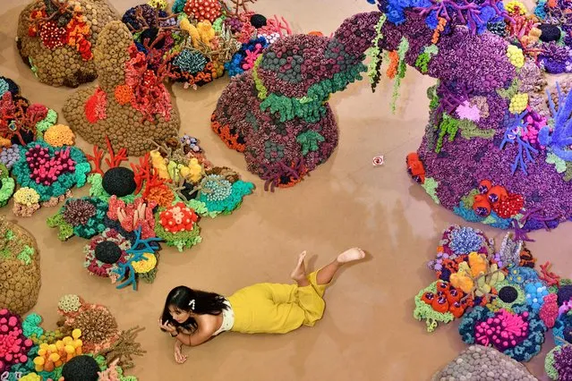 A visitor poses for photographs in front of the eco-art exhibition “Anima Mundi: Soul of the World” by Indonesian artist Mulyana in Bangkok on August 21, 2019. Mulyana uses discarded materials such as rubber and plastic for his marine creatures knitwork to raise awareness of the environment. (Photo by Mladen Antonov/AFP Photo)