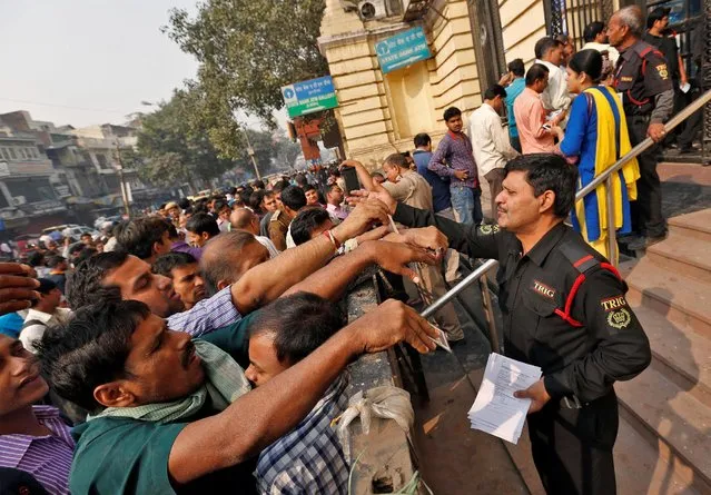 A security guard hands out request slips for the exchange of old high denomination bank notes at a branch of the State Bank of india in Old Delhi, India, November 10, 2016. (Photo by Cathal McNaughton/Reuters)