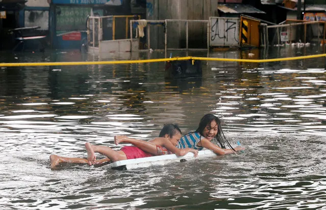 Children use a makeshift raft as they play along a partially flooded street caused by monsoon rains and Tropical Storm Son-Tinh in Quezon city, Metro Manila, in Philippines July 17, 2018. (Photo by Erik De Castro/Reuters)