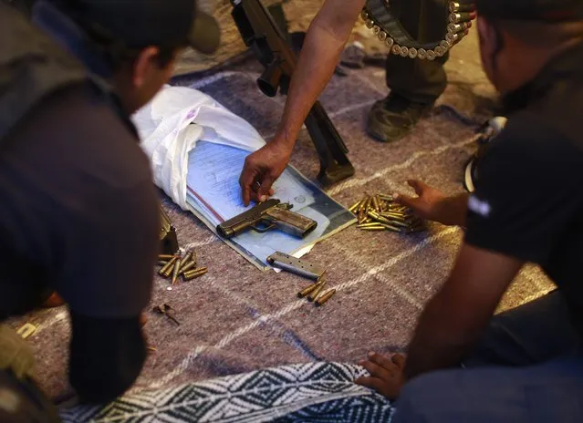 Members of the Community Police of the FUSDEG (United Front for the Security and Development of the State of Guerrero) lay out weapons and ammunition, which were found in a house, onto the ground during an operation in the village of Petaquillas, on the outskirts of Chilpancingo, in the Mexican state of Guerrero, February 1, 2015. (Photo by Jorge Dan Lopez/Reuters)