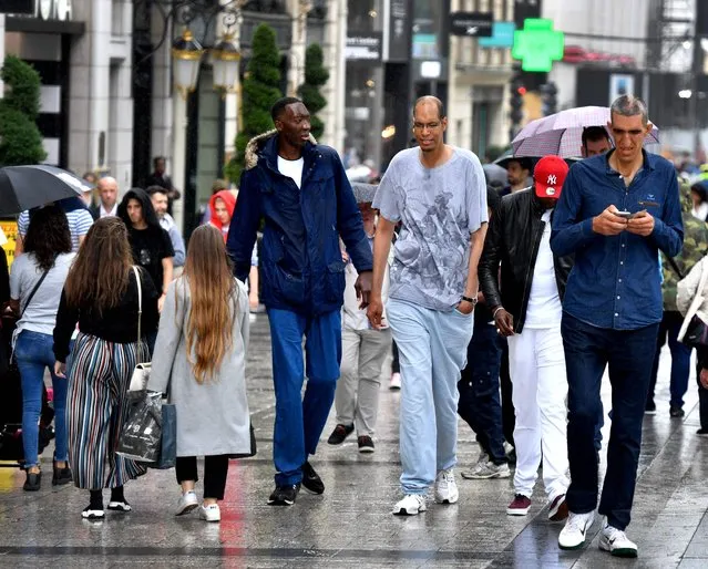(L to R) Ivory Coast's Abdramane Dembele, 2m35, France's Brahim Takioullah, 2m46 and Armenia's Arshavir Grigoryan, 2m33, walk in the crowd on the Champs-Elysees Avenue in Paris, on June 1, 2018. A dozen of the world's tallest people met in Paris for a weekend. (Photo by Gerard Julien/AFP Photo)