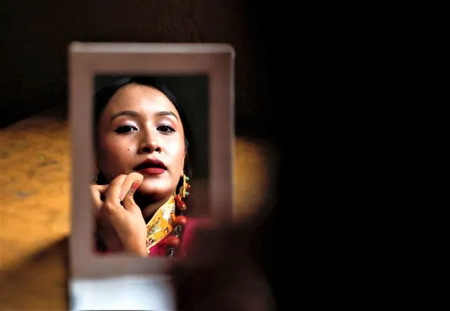 A Tibetan girl is reflected in a mirror, as she gets ready for her performance during an event organised to mark the 88th birthday celebration of their spiritual leader, the Dalai Lama in Kathmandu, Nepal on July 6, 2023. (Photo by Navesh Chitrakar/Reuters)