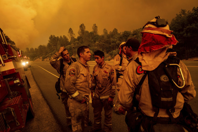 Firefighters discuss plans while battling the Carr Fire in Shasta, Calif., on Thursday, July 26, 2018. (Photo by Noah Berger/AP Photo)