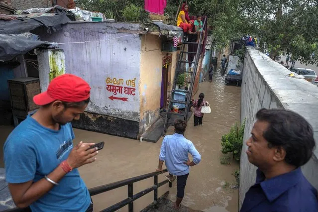 Residents stand outside their flooded houses by the rising waters of river Yamuna after heavy monsoon rains in New Delhi, India on July 11, 2023. (Photo by Adnan Abidi/Reuters)