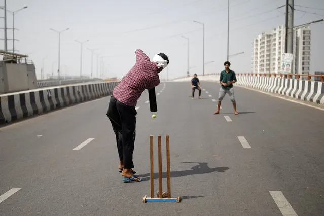 Farmers play cricket on a deserted highway road during a 12-hour strike, as part of protests against farm laws, at the Delhi-Uttar Pradesh border in Ghaziabad, India, March 26, 2021. (Photo by Adnan Abidi/Reuters)