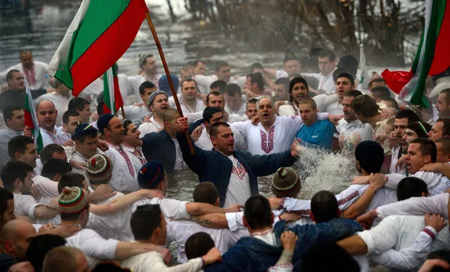 People perform the national dance 'Horo' holding national flags in the icy waters of the river in the town of Kalofer some 150 km from Sofia, Bulgaria, during celebrations of the Epiphany day on 06 January 2016. Epiphany is a Christian feast that celebrates the arrival of the Three Wise Men with their gifts for the infant Jesus. (Photo by Vassil Donev/EPA)