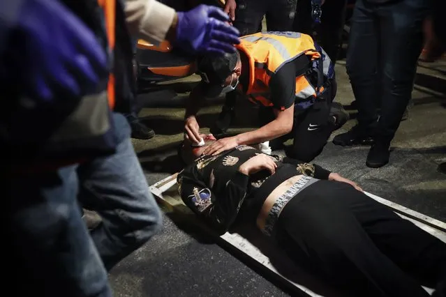 A wounded Palestinian demonstrator receives treatment after he was hit during clashes with Israeli police at Damascus Gate just outside Jerusalem's Old City, Thursday, April. 22, 2021. (Photo by Ariel Schalit/AP Photo)