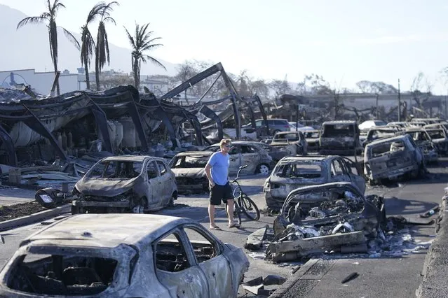 A man walks through wildfire wreckage Friday, August 11, 2023, in Lahaina, Hawaii.  Hawaii emergency management records show no indication that warning sirens sounded before people ran for their lives from wildfires on Maui that wiped out a historic town. (Photo by Rick Bowmer/AP Photo)