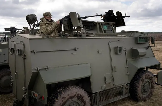 A serviceman inspects a Ukrainian weapon systems installed on a British Saxon armored personnel carrier vehicle during a presentation of new samples of Ukrainian-made weapons for the Ukrainian Army at a military base in Novi Petrivtsi outside Kiev, Ukraine, Saturday, April 4, 2015. (Photo by Efrem Lukatsky/AP Photo)