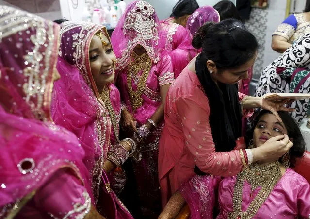 A Muslim bride gets her make-up done as others wait at a beauty parlour before the start of a mass marriage ceremony in Mumbai, India, January 27, 2016. (Photo by Danish Siddiqui/Reuters)