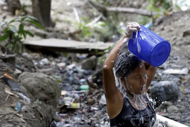 A woman takes a shower in a stream due to a water shortage in Panama City March 20, 2015. (Photo by Carlos Jasso/Reuters)