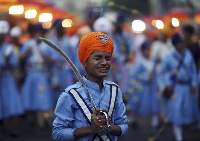 A Sikh boy reacts to a jovial comment from another as he prepares to display his martial art skills during a religious procession ahead of the birth anniversary of the first Sikh guru, Guru Nanak, in Hyderabad, India, Monday, November 19, 2018. The birth anniversary of Guru Nanak will be marked on Nov. 23. (Photo by Mahesh Kumar A./AP Photo)