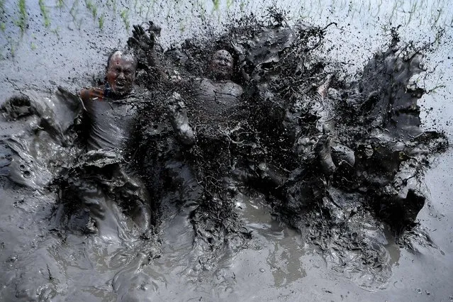 Mud-covered farmers play in a rice paddy field during “National Paddy Day”, which marks the start of the annual rice planting season, in Tokha village on the outskirts of Kathmandu on June 29, 2021. (Photo by Prakash Mathema/AFP Photo)