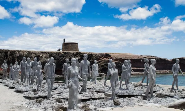 Sculptures that form part of the Rubicon installation are seen on land in Lanzarote. The final piece features a fence that the figures walk towards. The piece is about the dangers of climate change and the fence marks a point of no return – the figures walk towards it looking at mobile phones and not paying attention. (Photo by Jason deCaires Taylor)
