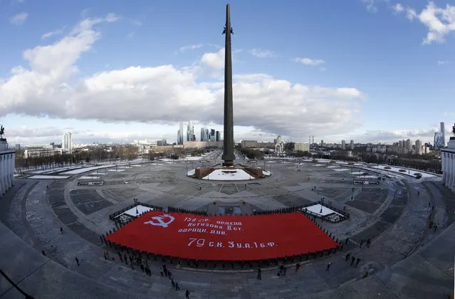 Cadets of the Russian Emergencies Ministry hold a giant replica of the so-called Victory Standard at the Poklonnaya Gora War Memorial Park, with buildings of the Moscow International Business Center, also known as "Moskva-City", seen in the background, in Moscow, Russia, February 4, 2016. The banner, measuring more than a thousand square meters, is the largest replica of the so-called Victory Standard in Russia, according to organizers. (Photo by Sergei Karpukhin/Reuters)