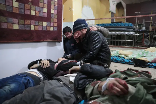 Syrian men mourn over the body of a relative at a makeshift hospital in the rebel-held town of Douma, on the eastern outskirts of Damascus, following reported air strikes on December 29, 2016. (Photo by Abd Doumany/AFP Photo)