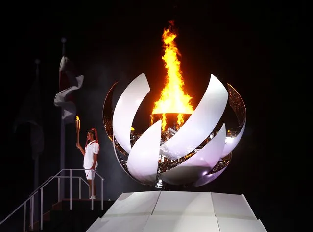 Naomi Osaka of Team Japan stands and waves with the Olympic flame during the Opening Ceremony of the Tokyo 2020 Olympic Games at Olympic Stadium on July 23, 2021 in Tokyo, Japan. (Photo by Kai Pfaffenbach/Reuters)