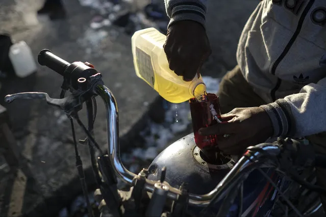 A man pours a small amount of gasoline into his motorcycle amid gas shortages in the La Saline neighborhood of Port-au-Prince, Haiti, Monday, July 19, 2021. (Photo by Matias Delacroix/AP Photo)