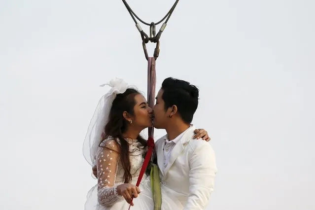 Groom Kittinant Suwansiri, 29, kisses his bride Jintara Promchat, 28, as they fly while attached to cables during a wedding ceremony ahead of Valentine's Day at a resort in Ratchaburi province, Thailand, February 13, 2016. (Photo by Athit Perawongmetha/Reuters)