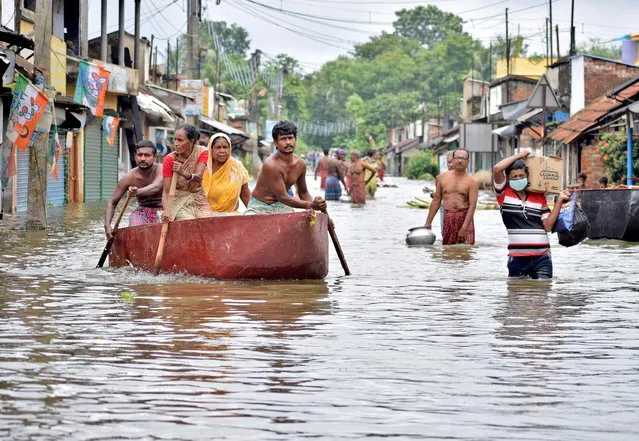 People wade through a flooded street to collect food and drinking water from a distribution centre in Amta town of Howrah district in the eastern state of West Bengal, India, August 5, 2021. (Photo by Reuters/Stringer)