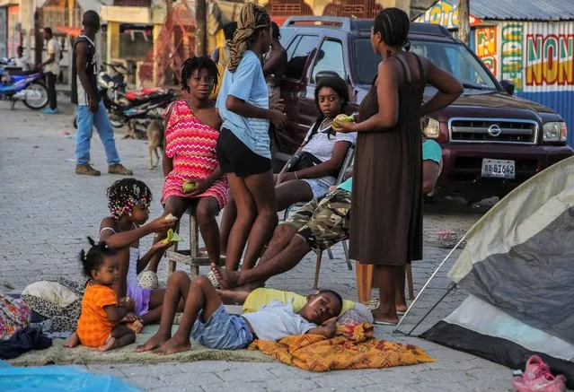 Locals eat after spending the night in the middle of a street after Saturday´s  7.2 magnitude earthquake in Les Cayes, Haiti, Sunday, August 15, 2021. (Photo by Joseph Odelyn/AP Photo)