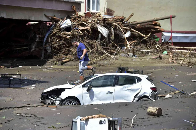 A man checks his car buried in the mud after floods and mudslides killed about three dozens of people, in Bozkurt town of Kastamonu province, Turkey, Friday, August 13, 2021. The death toll from devastating floods and mudslides in northern Turkey rose to at least 31 on Friday, officials said, as emergency services searched for survivors in collapsed buildings or swamped homes, shops and basements. An opposition politician said more than 300 people may be unaccounted-for. (Photo by AP Photo/Stringer)