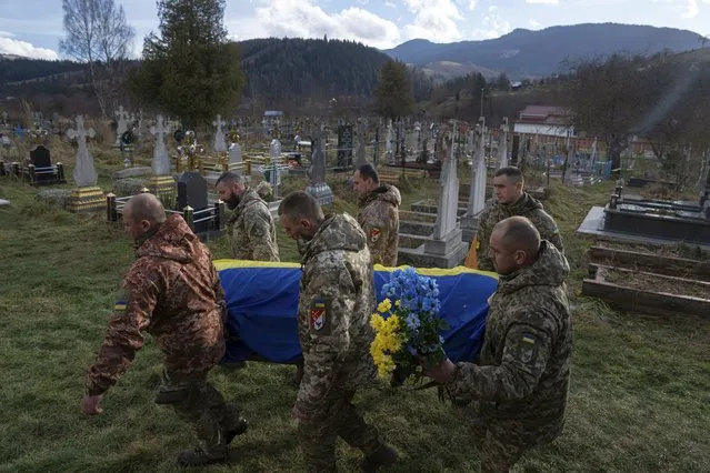 Ukrainian servicemen carry the coffin of their comrade Vasyl Boichuk who was killed in Mykolayiv in March 2022, during his funeral ceremony at the cemetery in Iltsi village, Ukraine, Tuesday, December 26, 2023. (Photo by Evgeniy Maloletka/AP Photo)