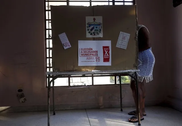 A woman marks her ballot at a polling station at a school in Havana April 19, 2015. The municipal elections take place in Cuba today. The sign reads “Election for municipal delegates. Vote for 2015 Cuba”. (Photo by Reuters/Stringer)