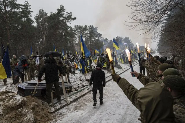 Funeral workers down a coffin into a grave during a funeral ceremony of Sviatoslav Romanchuk, Ukrainian serviceman, at the cemetery in Kyiv, Ukraine, Wednesday, January 3, 2024. Romanchuk joined territorial defence since the beginning of or Russian invasion and was killed on Dec. 28, 2023 in Lyman direction, Donetsk region. (Photo by Evgeniy Maloletka/AP Photo)