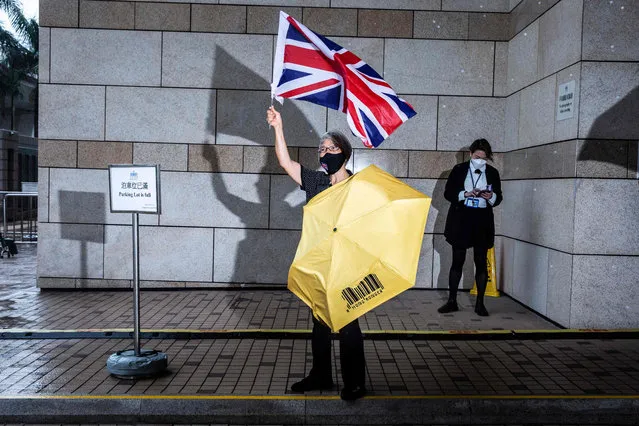 Pro-democracy activist Alexandra Wong (C) holds up a Union Jack flag outside West Kowloon court in Hong Kong on September 23, 2021, where 47 pro-democracy defendents appear in court charged with conspiracy to commit subversion under the Beijing enacted national security law. (Photo by Isaac Lawrence/AFP Photo)