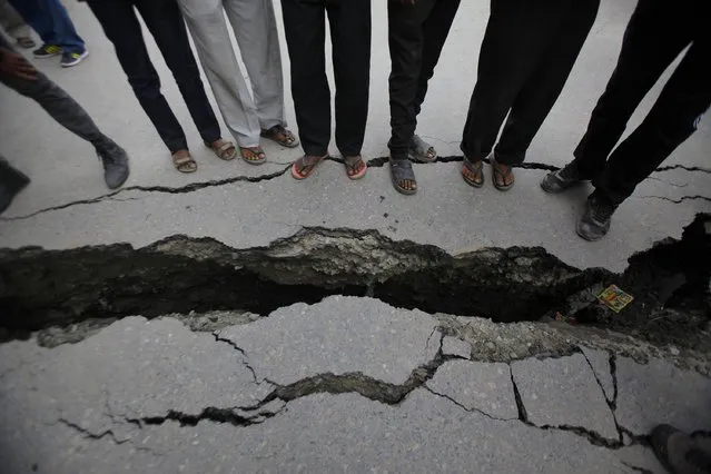 Nepalese people look at a cracked road after an earthquake in Kathmandu, Nepal, Sunday, April 26, 2015. (Photo by Niranjan Shrestha/AP Photo)