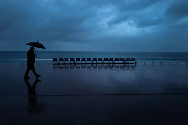 A pedestrian holding an umbrella walks along the “Promenade des Anglais” in the French Riviera city of Nice, on December 4, 2023. (Photo by Valery Hache/AFP Photo)