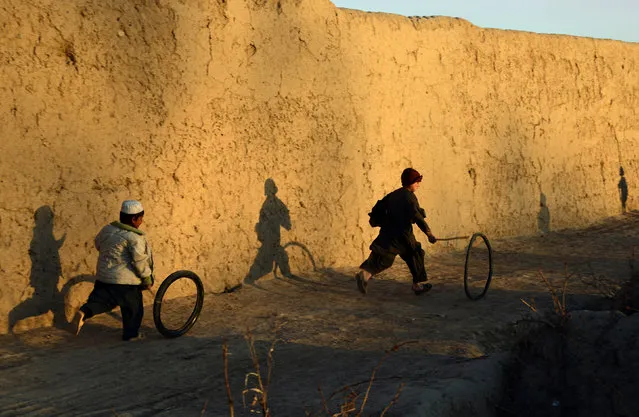 In this photograph taken on February 22, 2016 Afghan boys play with a tyre outside their house in the Zhari district of Kandahar province. (Photo by Javed Tanveer/AFP Photo)