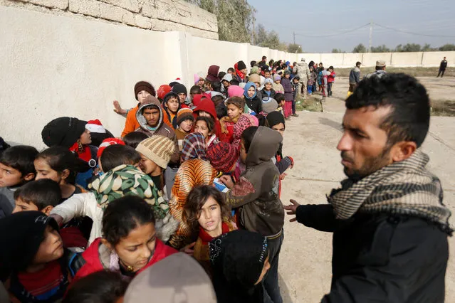 Iraqi children stand in line to receive aid during a battle with Islamic State militants in Rashidiya, north of Mosul, Iraq, January 30, 2017. (Photo by Muhammad Hamed/Reuters)