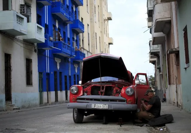 A man repairs his 1954 Chevrolet car on a street in Havana March 15, 2016. (Photo by Enrique de la Osa/Reuters)