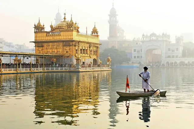 A Sikh volunteer cleans the holy sarovar or sacred pool on the occasion of the birth anniversary of Guru Nanak Dev, the founder of Sikhism, at the Golden Temple in Amritsar on November 19, 2021. (Photo by Narinder Nanu/AFP Photo)