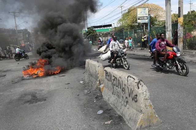 Motorists pass by a burning barricade during a protest as the government said it would extend a state of emergency for another month after an escalation in violence from gangs seeking to oust the Prime Minister Ariel Henry, in Port-au-Prince, Haiti, on March 7, 2024. (Photo by Ralph Tedy Erol/Reuters)