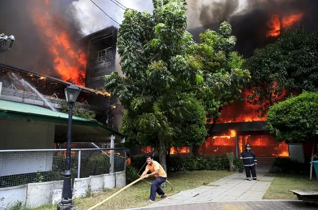 A man pulls a fire hose as a firefighter tries to put out a fire as it razes the College of Arts and Sciences building of the University of the East in Manila April 2, 2016. (Photo by Romeo Ranoco/Reuters)
