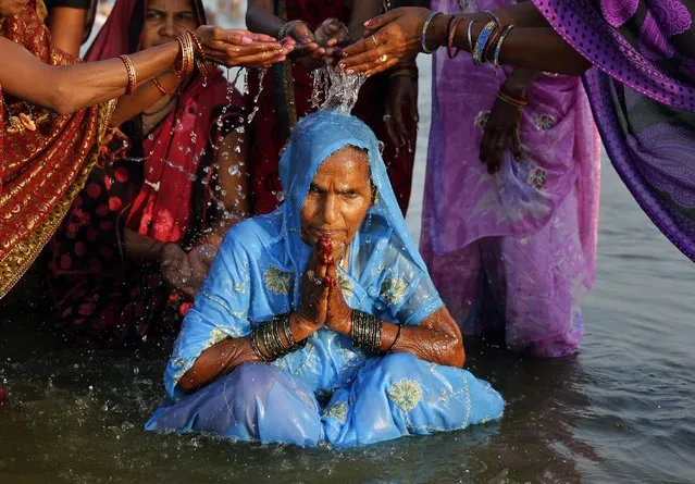 Indian Hindu devotees help bathe an elderly woman as they perform rituals in the the river Ganges on Somvati Amavasya, or no moon day, in Allahabad, India, Monday, May 18, 2015. (Photo by Rajesh Kumar Singh/AP Photo)