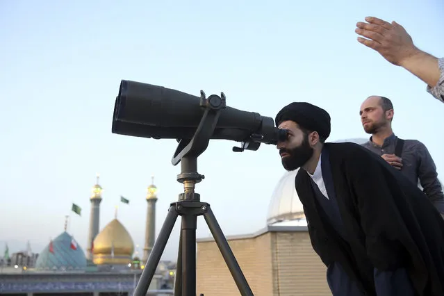 A cleric looks through binoculars to sight the new moon that signals the start of the Islamic holy fasting month of Ramadan, at the shrine of the Shiite Saint Imam Abdulazim in Shahr-e-Ray, south of Tehran, Iran, Sunday, May 5, 2019. (Photo by Ebrahim Noroozi/AP Photo)
