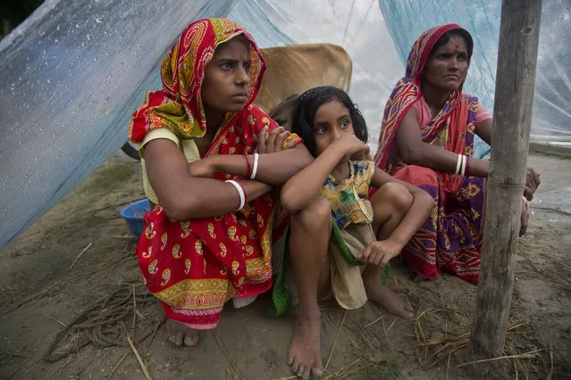 Flood effected villagers take shelter under a makeshift tent on a highland in Katahguri village along the river Brahmaputra, east of Gauhati, India, Sunday, July 14, 2019. Officials in northeastern India said more than a dozen people were killed and over a million affected by flooding. Rain-triggered floods, mudslides and lightning have left a trail of destruction in other parts of South Asia. (Photo by Anupam Nath/AP Photo)