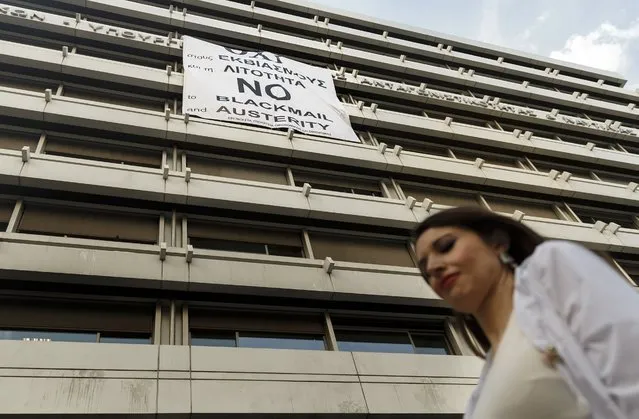 A woman passes a banner supporting the NO vote to the upcoming referendum at the Finance Ministry in Athens, Wednesday, July 1, 2015. Greece's government appeared to be caving into demands from its creditors on Wednesday, offering concessions in a desperate attempt to get more aid hours after its bailout program expired. (Photo by Daniel Ochoa de Olza/AP Photo)