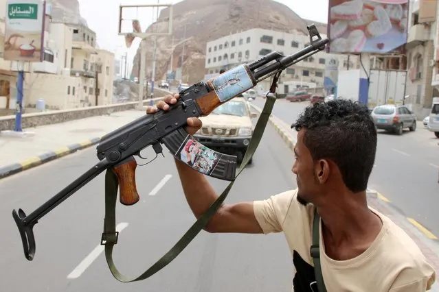 A member of Yemen's southern separatist holds his weapon with a picture of Muneer al-Yafee during a funeral of Brigadier General Muneer al-Yafee and his comrades killed in a Houthi missile attack, in Aden, Yemen, August 7, 2019. (Photo by Fawaz Salman/Reuters)
