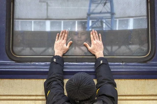 Aleksander, 41, presses his palms against the window as he says goodbye to his daughter Anna, 5, on a train to Lviv at the Kyiv station, Ukraine, Friday, March 4. 2022. Aleksander has to stay behind to fight in the war while his family leaves the country to seek refuge in a neighboring country. (Photo by Emilio Morenatti/AP Photo)