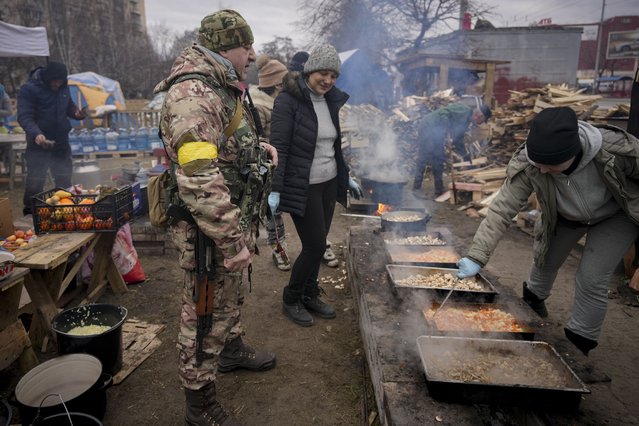 People cook outdoors for the Ukrainian servicemen and civil defense members serving in Kyiv, Ukraine, Monday, March 7, 2022. The United Nations is unable to meet the needs of millions of civilians caught in conflict in Ukraine today and is urging safe passage for people to go “in the direction they choose” and for humanitarian supplies to get to areas of hostilities, according to the U.N. humanitarian chief. (Photo by Vadim Ghirda/AP Photo)
