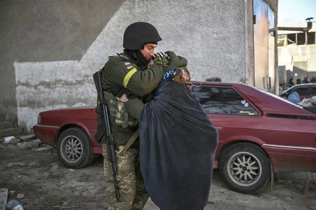 A Ukranian soldier hugs his wife in the city of Irpin, north of Kyiv, on March 10, 2022. Russian forces on March 10, 2022 rolled their armoured vehicles up to the northeastern edge of Kyiv, edging closer in their attempts to encircle the Ukrainian capital. Kyiv's northwest suburbs such as Irpin and Bucha have been enduring shellfire and bombardments for more than a week, prompting a mass evacuation effort. (Photo by Aris Messinis/AFP Photo)